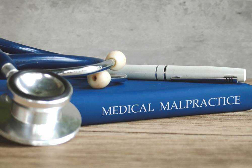 Stethoscope and a pen on a book titled MEDICAL MALPRACTICE, representing legal issues in healthcare.