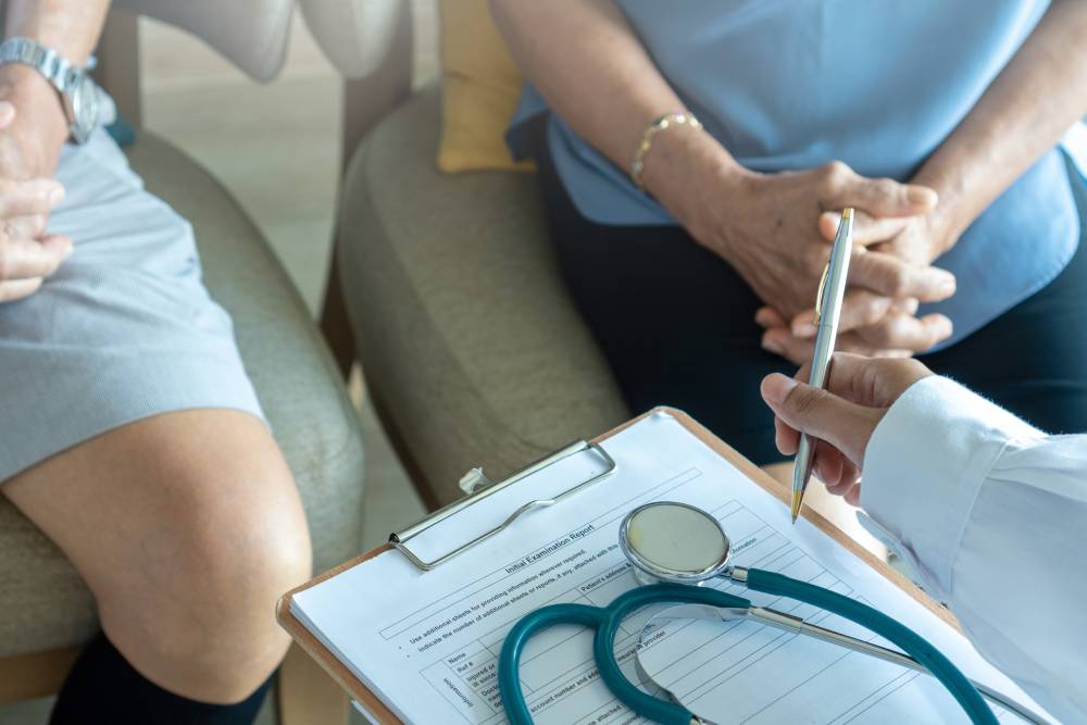 Doctor physician with elderly senior patient knee problem in hospital examination room or hospice nursing home or wellbeing county.