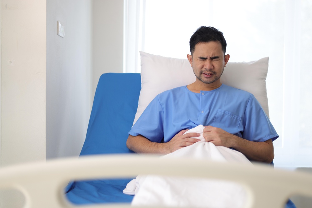Patient suffering from abdominal pain in hospital bed